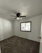 Empty room featuring dark carpet and a textured ceiling