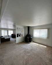 Carpeted living room with a wood stove and a textured ceiling