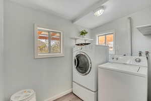 Laundry room with washer and dryer, vaulted ceiling, and light wood-style floors