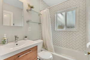 Bathroom featuring vanity and shower / bathtub combination with curtain