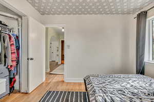 Bedroom featuring light wood-style floors, arched walkways, a closet, and multiple windows