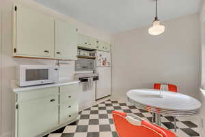Kitchen with green cabinets, light floors, pendant lighting, and light countertops