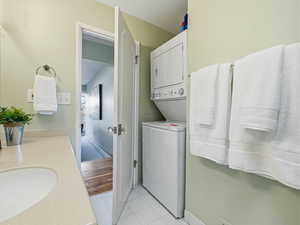 Bathroom featuring stacked washer / drying machine, vanity, and light tile patterned floors
