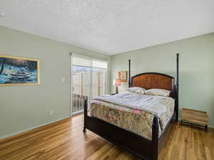 Bedroom featuring access to outside, hardwood / wood-style flooring, and a textured ceiling