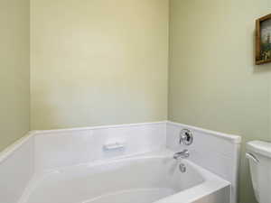 Bathroom featuring a garden tub and toilet