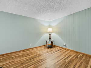Empty room with wood finished floors and a textured ceiling