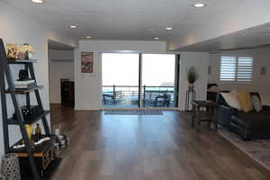Living area featuring dark wood-type flooring, plenty of natural light, a wall mounted air conditioner, recessed lighting, and a textured ceiling