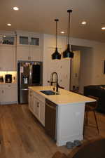 Kitchen with dark wood-style flooring, white cabinets, appliances with stainless steel finishes, glass insert cabinets, and recessed lighting