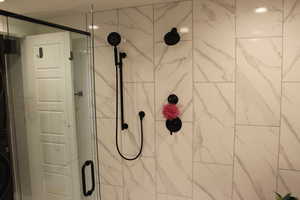 Detailed view of a shower stall and estacked washer and dryer