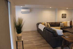 Living room with recessed lighting, wood finished floors, and a wall mounted air conditioner