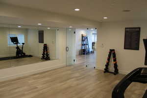 Workout room with wood finished floors and recessed lighting