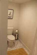 Bathroom featuring toilet and light marble finish flooring