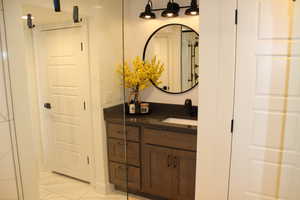 Bathroom with vanity, light marble finish floors, and a shower