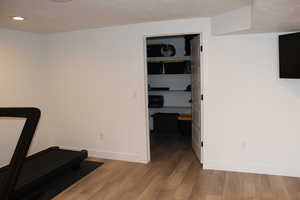 Exercise area featuring light wood finished floors and a textured ceiling