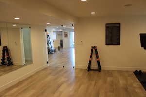 Workout room with recessed lighting and light wood-type flooring