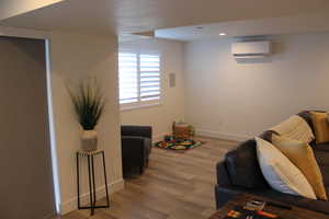 Living area featuring an AC wall unit, wood finished floors, and recessed lighting