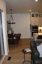 Living room with light wood-type flooring, a chandelier, and recessed lighting