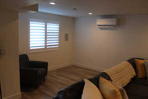 Living area featuring dark wood-style floors, recessed lighting, and an AC wall unit