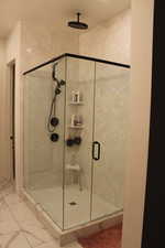 Bathroom featuring a stall shower and light marble finish floors