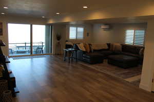 Living area featuring recessed lighting, dark wood-style flooring, healthy amount of natural light, and a wall unit AC