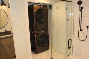 Laundry area featuring stacked washer / dryer and marble finish floors