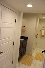 Bathroom with vanity, light marble finish flooring, and recessed lighting
