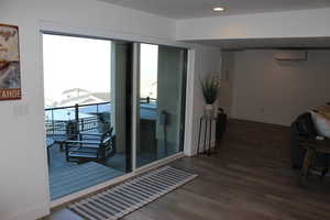 Doorway with wood finished floors, a wall unit AC, and recessed lighting