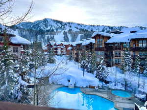 Snowy aerial view with a mountain view and view of pool area