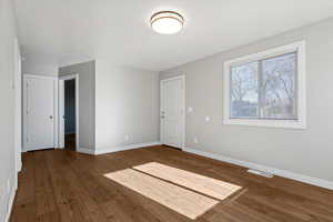 Unfurnished bedroom with baseboards and hardwood / wood-style flooring