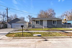View of front of home with a fenced front yard, an outbuilding, and a garage