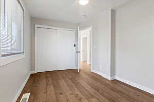 Unfurnished bedroom with hardwood / wood-style flooring, ceiling fan, and a closet