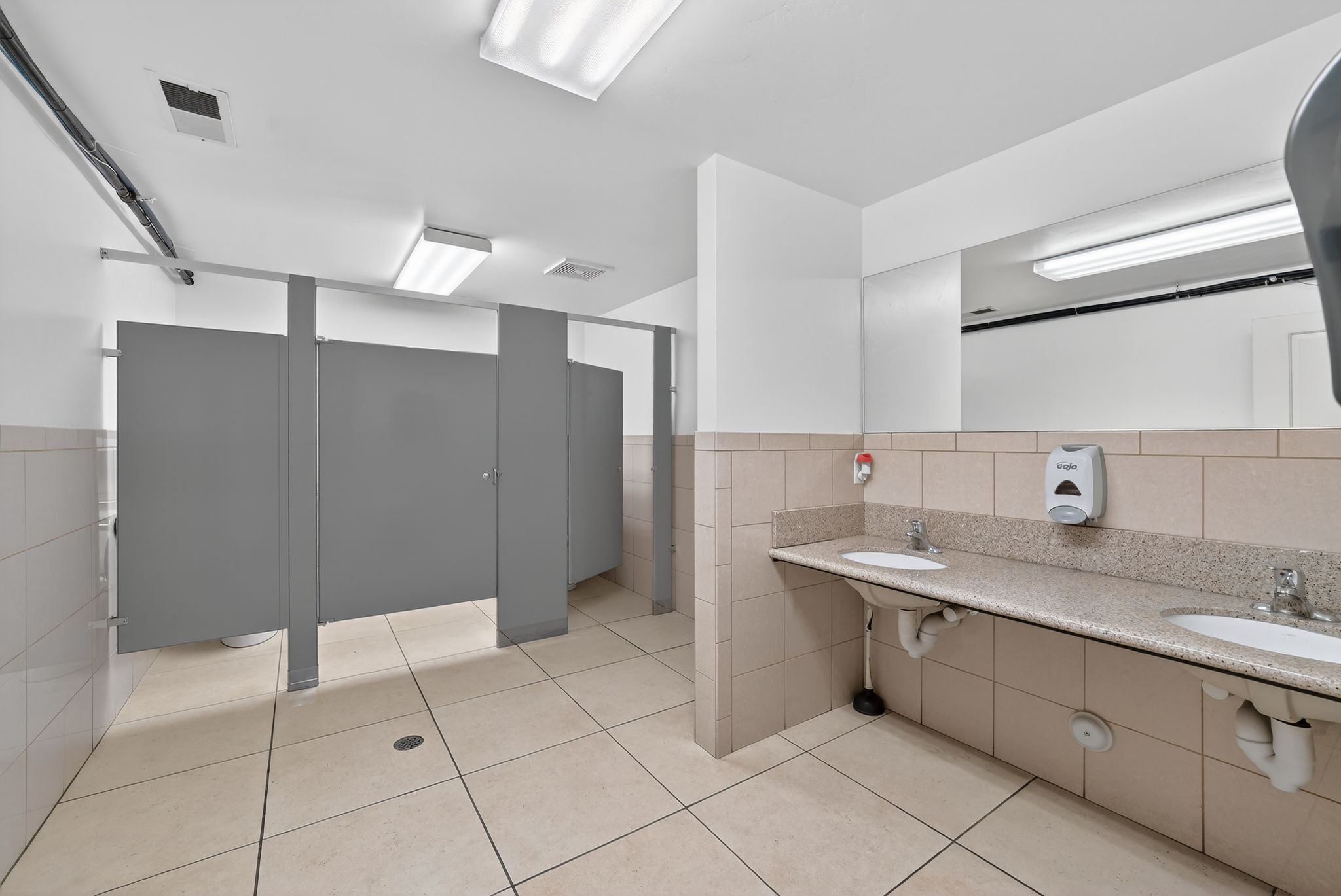 Full bathroom featuring tile walls, double vanity, wainscoting, and a shower stall