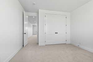Unfurnished bedroom featuring light carpet and a closet