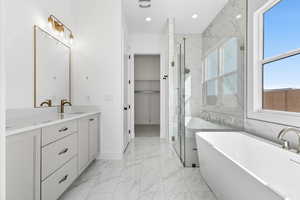 Full bath with a shower stall, a freestanding bath, a spacious closet, light marble finish flooring, and vanity