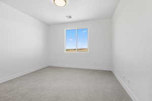 Empty room featuring light colored carpet and baseboards
