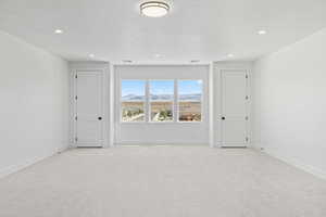 Spare room with light colored carpet, a mountain view, recessed lighting, and a textured ceiling