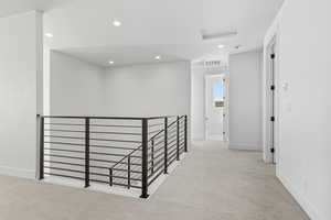 Corridor with an upstairs landing, light colored carpet, and recessed lighting