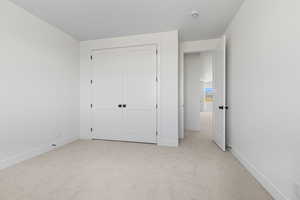 Unfurnished bedroom with light carpet and a closet