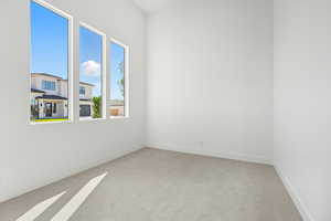 Empty room with light colored carpet and baseboards