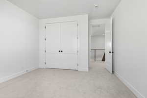 Unfurnished bedroom with light carpet and a closet