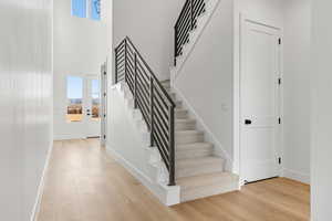 Stairs featuring a towering ceiling, healthy amount of natural light, and wood finished floors