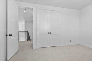 Unfurnished bedroom featuring light colored carpet, a closet, and recessed lighting