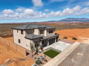 View of front of house featuring stucco siding, a mountain view, driveway, a garage, and view of desert landscape