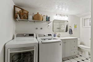 Laundry room featuring a textured ceiling, washer and clothes dryer, and vaulted ceiling