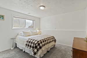 Carpeted bedroom with baseboards and a textured ceiling