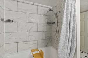 Bathroom with shower / tub combo and a textured ceiling