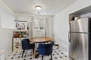 Dining room with light flooring and a textured ceiling