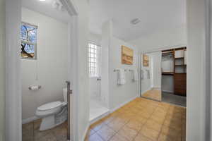 Full bath with light tile patterned flooring, a spacious closet, and a walk in shower