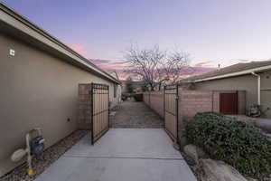 View of side of home with a gate, stucco siding, and a patio