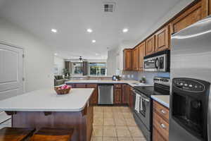 Kitchen featuring appliances with stainless steel finishes, a breakfast bar area, light countertops, a ceiling fan, and recessed lighting